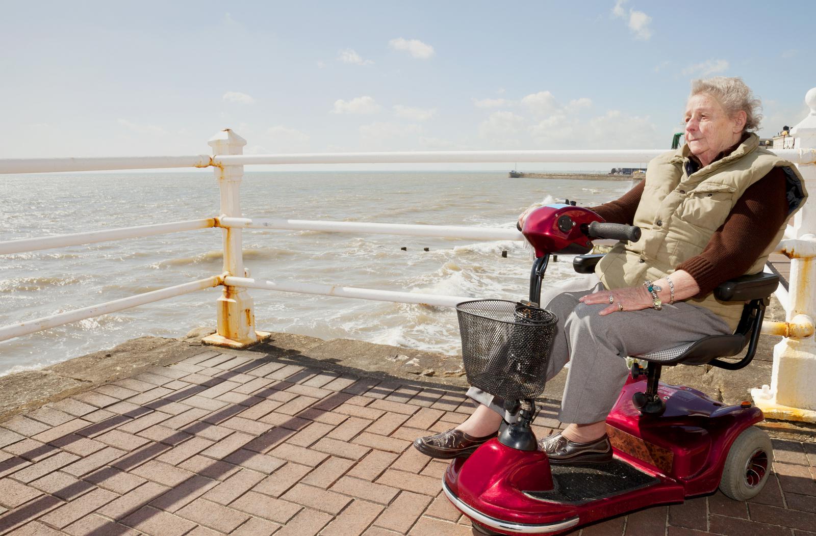 Woman using her mobility scooter on a dock near the ocean
